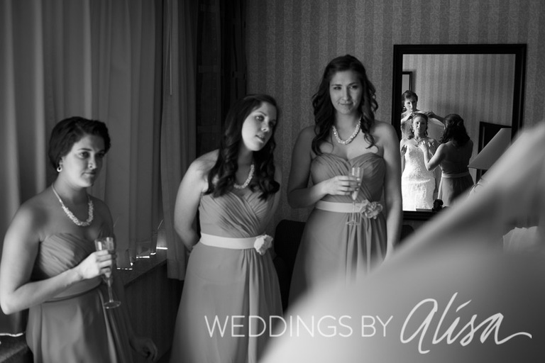 Bridesmaids looking at bride getting ready